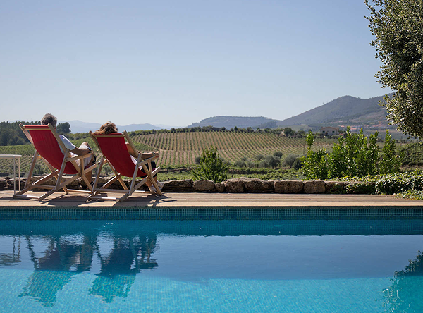 Couple relaxing poolside with vineyard views
